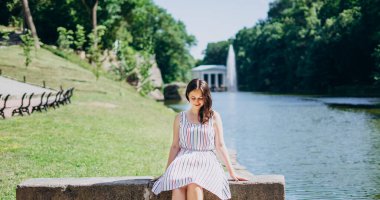 Sofia Park, Uman. Gölün arkasındaki bankta oturan güzel bir kız. Nehrin arka planında taştan bir bankta oturan bir kız ve beyaz bir çardak..
