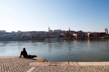 Budapeşte nehir kıyısında oturan adam