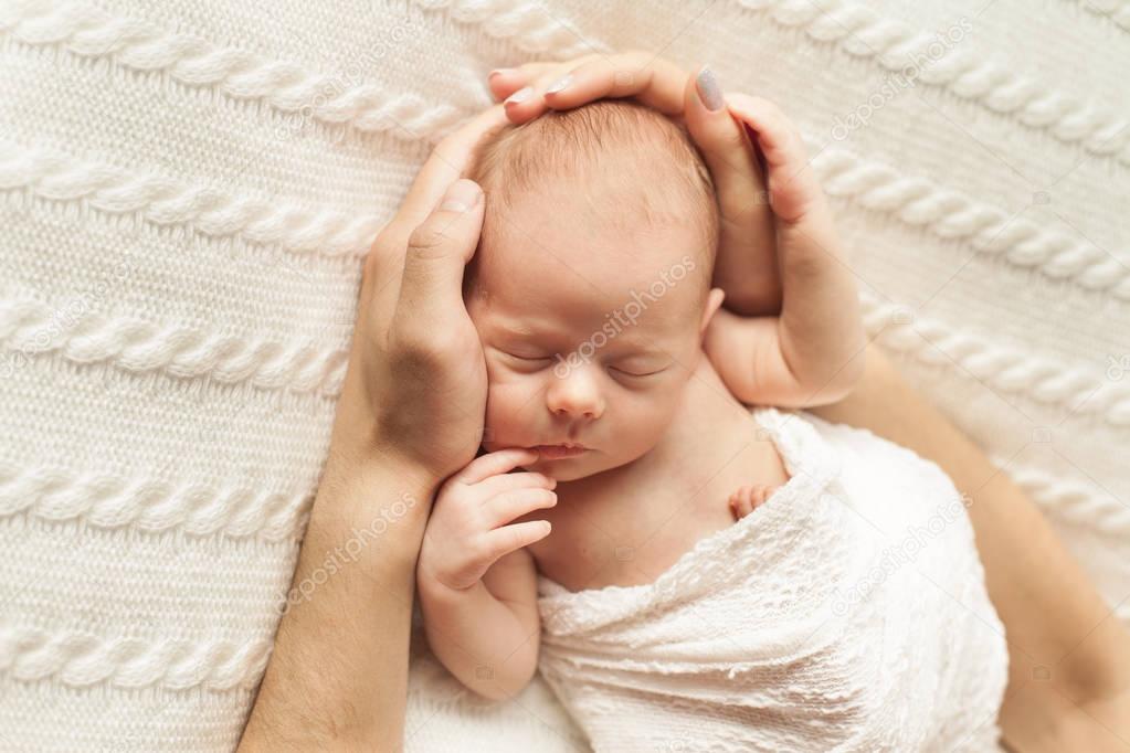 parents hands holding newborn