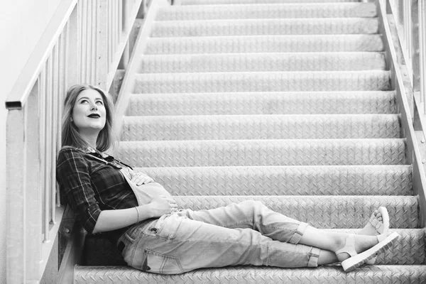 Беременная девушка сидит на лестнице — стоковое фото