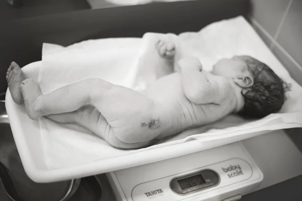 Новорожденный ребенок лежит на весах — стоковое фото
