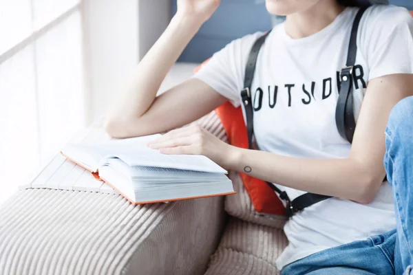 Una joven con una camiseta blanca está leyendo un libro. Es una estudiante inteligente y diligente. Primer plano . —  Fotos de Stock