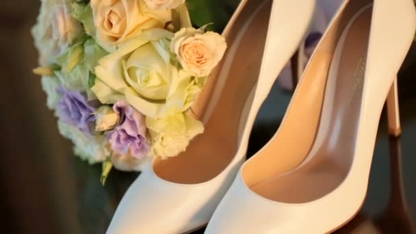 Beige wedding shoes stand by the bouquet in rays of evening sun — ストック動画