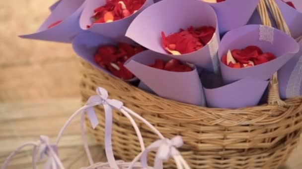 Violet envelopes with red petals stand in a basket — Stockvideo