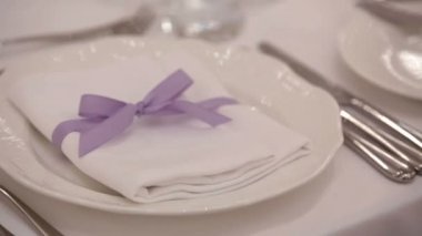Mor kurdele ile beyaz peçete yemek tabağı üzerinde yatıyor