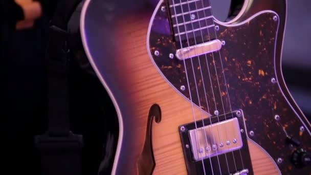 Las luces violetas iluminan la guitarra de madera — Vídeos de Stock