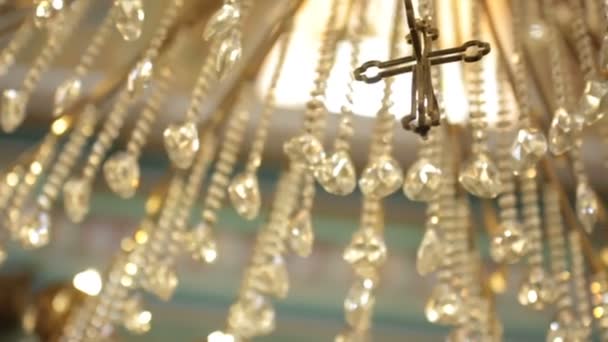 Croix en acier suspendue à un lustre en cristal dans l'église — Video