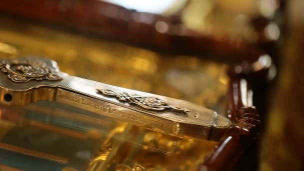 Cruz de bronce se encuentra en la mesa de cristal en la iglesia — Vídeos de Stock