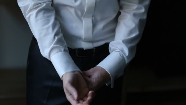 Man adjusts his sleeves in dark room — Stock Video