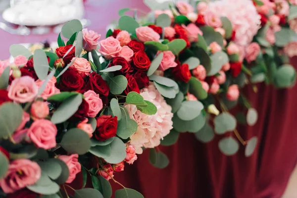 Festa de flores com rosas maravilhosas jaz na mesa de jantar vermelha — Fotografia de Stock