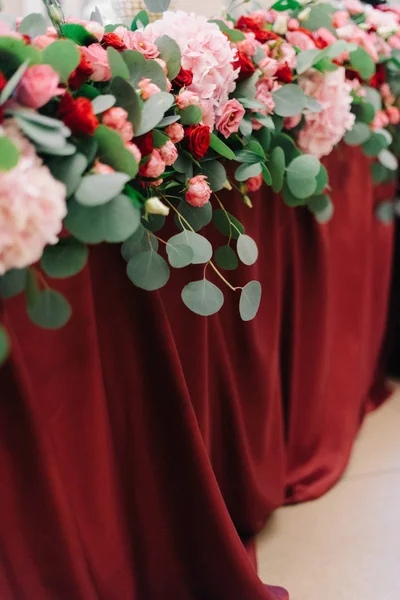Festa de flores verde e vermelha jaz na mesa de jantar — Fotografia de Stock