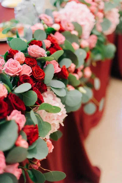 Festa de flor com vegetação encontra-se na mesa de jantar vermelho — Fotografia de Stock
