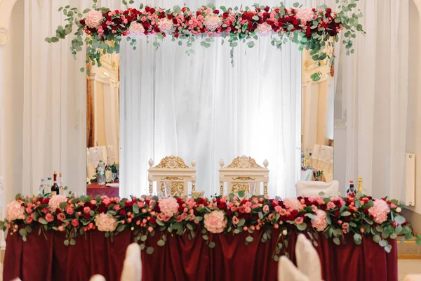 Mesa de cena rica decorada con festón de flores rojas — Foto de Stock