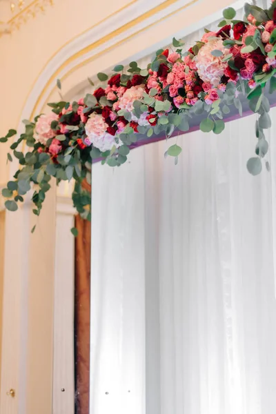 Fenêtre lumineuse décorée avec un feston de fleurs rouges — Photo