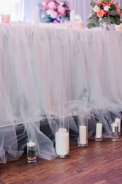 Velas brancas em vasos altos ficam diante da mesa sob o véu — Fotografia de Stock