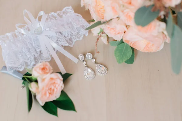 Prach rozen, witte Kousenband en crystal oorbellen liggen op de vloer — Stockfoto