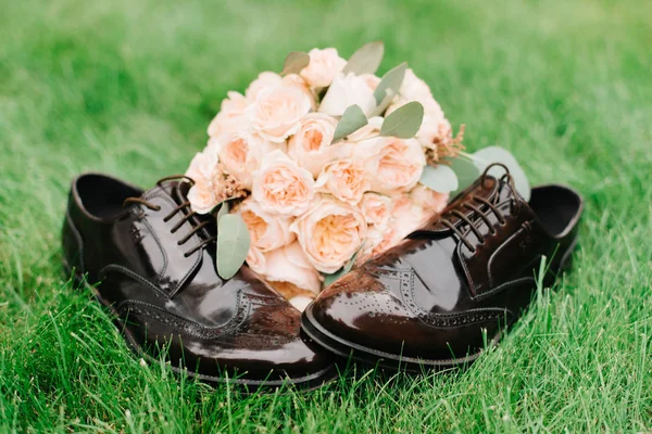 Peach wedding bouquet lies on lacquer shoes