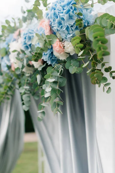 Blue and pink hydrangeas hang from wedding altar