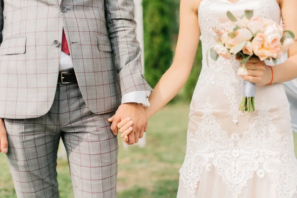 Fecho do noivo em terno xadrez segurando a mão de noivas — Fotografia de Stock