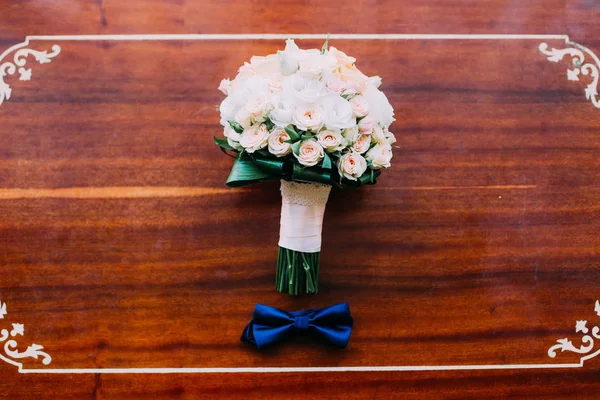 Gravata de arco e buquê de casamento de rosas na mesa de madeira rústica. Conceito de casamento. Filtro retrô . — Fotografia de Stock