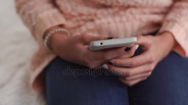 Jovem sentada na cama e tomando telefone em suas mãos — Vídeo de Stock
