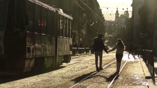 美しい幸せなスタイリッシュなカップル歩いて、冬の朝のヨーロッパの都市の路上で手を繋いでいます。ウクライナ リヴィウ市 — ストック動画