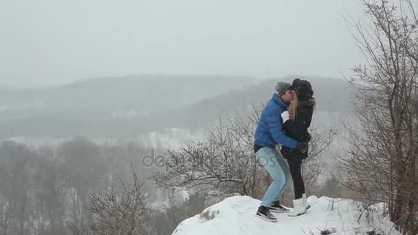 年轻的快乐情侣接吻和拥抱在冬季白雪皑皑的森林 — 图库视频影像