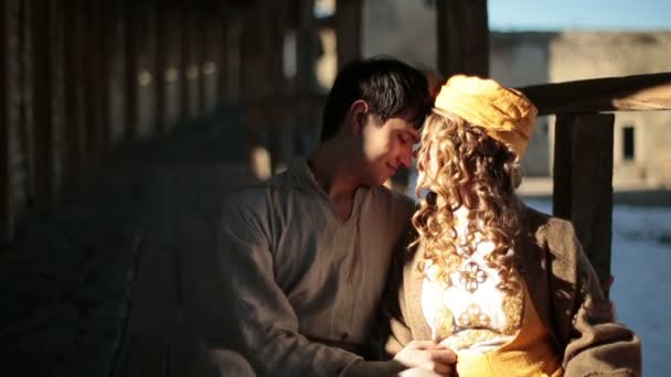Романтическая пара в традиционном костюме мягко целуется в старом средневековом замке — стоковое видео