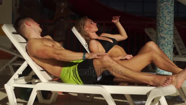 Pár chatování na lehátka u bazénu. krásný muž a žena se smíchem a chatování. — Stock video