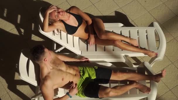 Paar plaudert auf Sonnenliegen in der Nähe des Pools. schöner Mann und Frau lachen und plaudern. — Stockvideo