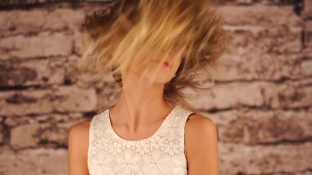 jeune adolescente secoue la tête, joue avec les cheveux et regarde la caméra. Le vent souffle et ses cheveux flottent .