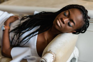 güzel Afrikalı kadın kanepede Kapalı gözlerle yalan. O uzun kirpiklere ve saç vardır.