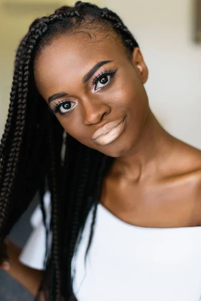 Porträtfoto eines afrikanischen Mädchens im weißen Kleid, das in die Kamera blickt und mit haarweißen Lippen spielt. große Augen. — Stockfoto