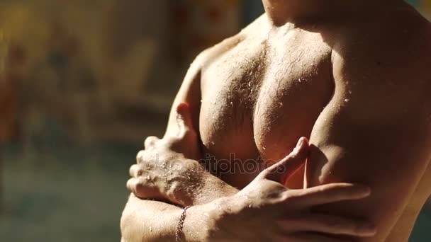 Um tipo sexy pôs as mãos no peito. Torso forte molhado, gotas de água fluindo através de seu corpo — Vídeo de Stock