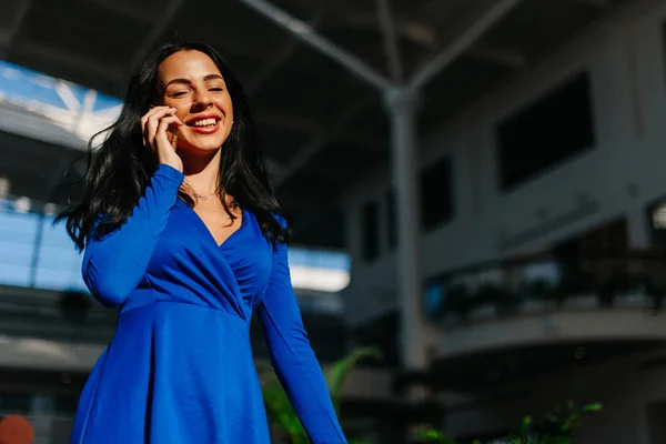 Foto retrato de menina bonita em vestido azul com mangas compridas depois de fazer compras no shopping e falar por telefone . — Fotografia de Stock