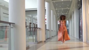 Turuncu elbise mağaza, yürüyüş ve onun mutluluğu gösterilen genç Afro-Amerikan kız