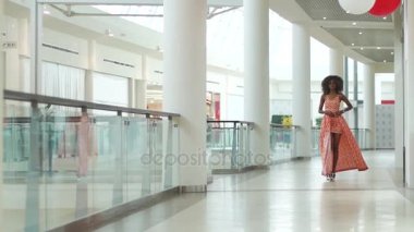 Güzel genç Afro-Amerikan kız catwalking ve onu turuncu akıllı yapmak daha kısa elbise