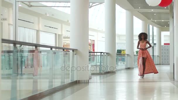 Hermosa chica afro-americana joven paseando y haciendo su vestido naranja inteligente más corto — Vídeos de Stock