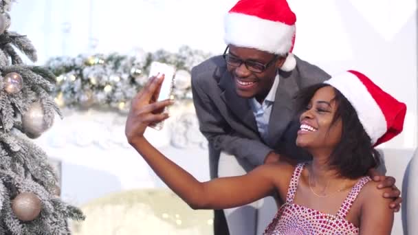 Happy young african family in Christmas atmosphere making selfi with smartphone. Amazing decorations. New Year tree — Stock Video