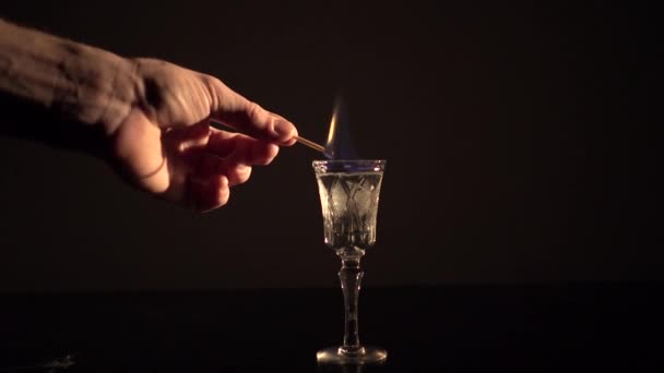 Strong hand is burning up an alcohol drink — Stock Video