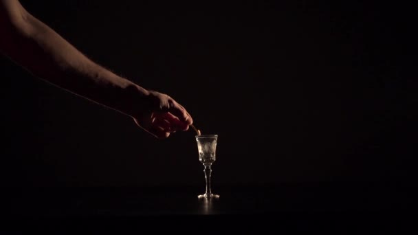 Strong hand is slowly burning up an alcohol drink — Stock Video