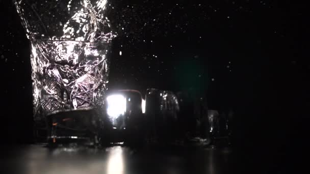 Бризки крижаного куба в склянці води в темряві — стокове відео