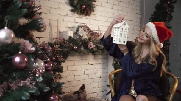 Jonge sexy meisje kijkt een decoraties in de buurt van de kerstboom — Stockvideo