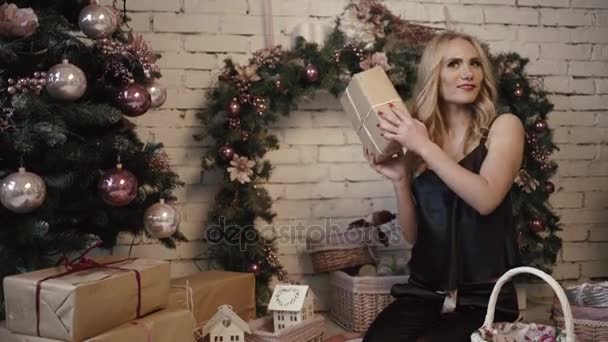 Joven chica sexy está mirando por encima de sus regalos de Navidad cerca del árbol de Año Nuevo — Vídeo de stock