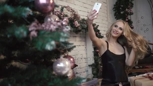 Jonge sexy meisje is het maken van selfies in de buurt van het Nieuwjaar boom — Stockvideo