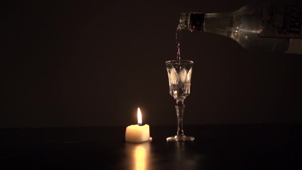 Verter sambuka en un vaso cerca de la vela encendida — Vídeo de stock