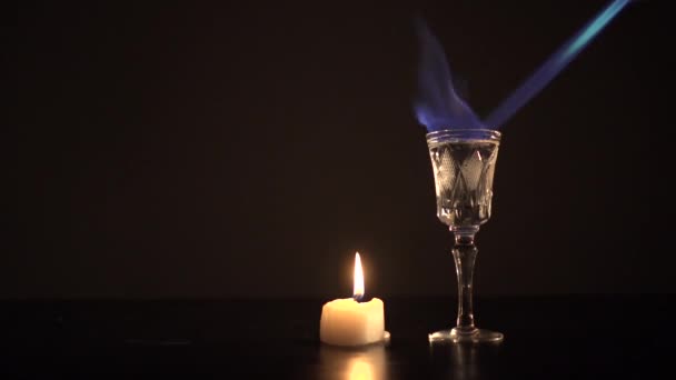 Горящий самбука с газовой зажигалкой возле маленькой свечи — стоковое видео