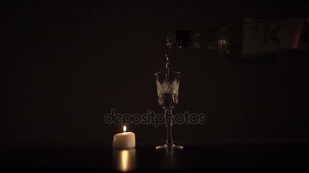 Verter sambuka en un vaso cerca de la vela encendida — Vídeo de stock