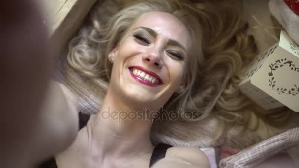 Menina sexy nova está deitada entre presentes, sorrindo e fazendo vídeo de si mesma — Vídeo de Stock