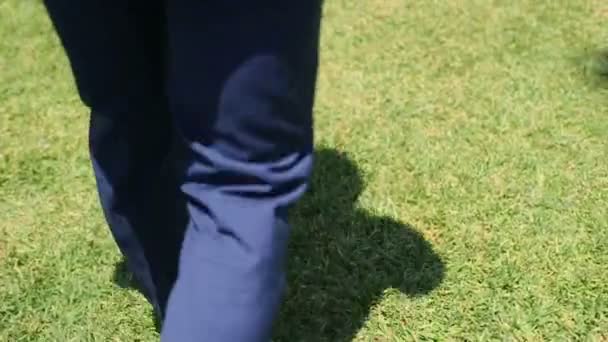 El novio con elegantes zapatos retro y traje azul camina sobre césped de hierba verde. Vista trasera. Día de la boda — Vídeos de Stock